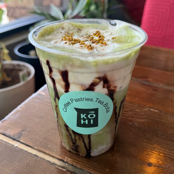 Iced matcha latte with whipped cream, chocolate drizzle, and crunchy toppings from KOHI Coffee.